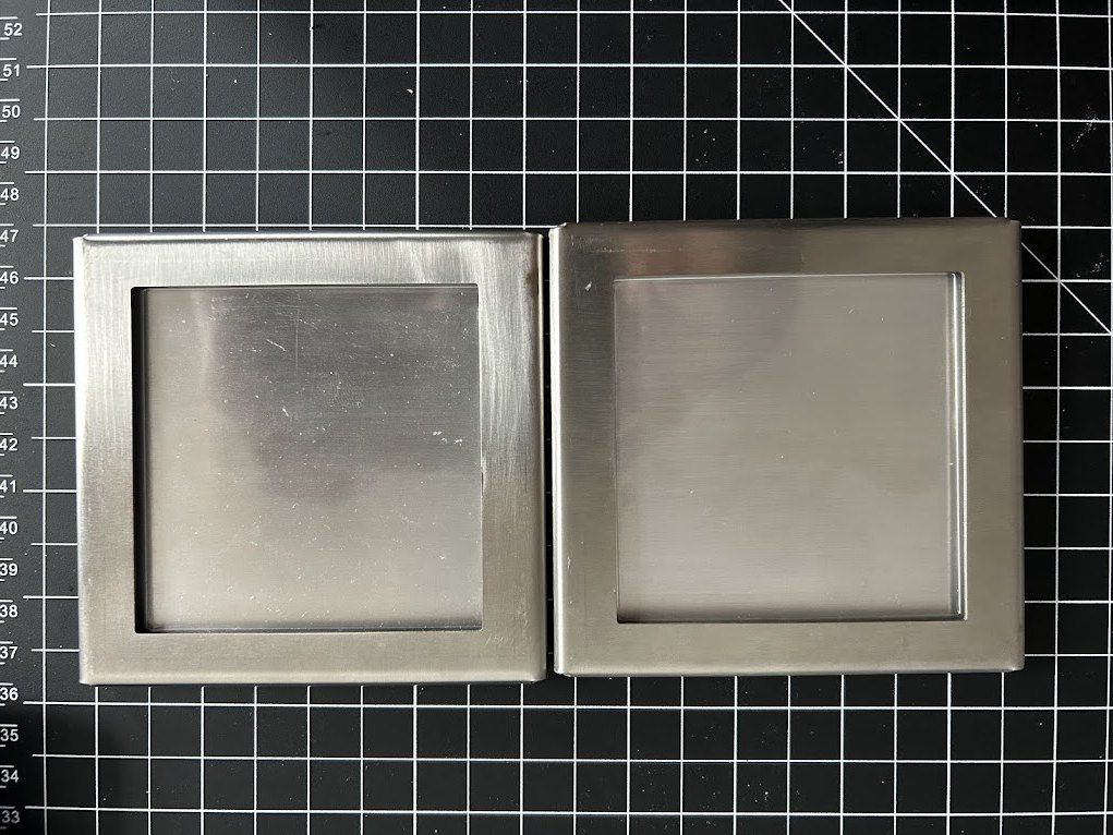 Two brushed stainless guard frames on a cutting mat
